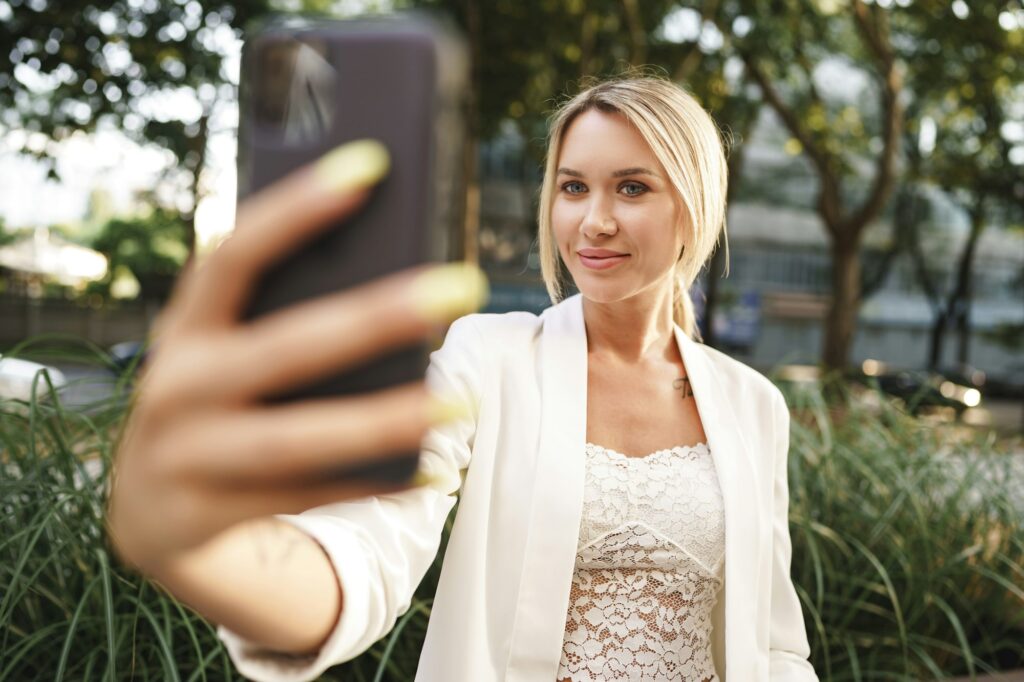 Beautiful young blonde businesswoman using smartphone in the city