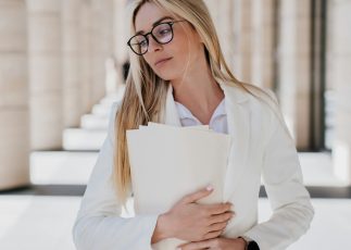 Tired blonde student woman in white suit and glasses standing outside during break. Frustrated Tired blonde student woman in white suit and glasses standing outside during break. Frustrated